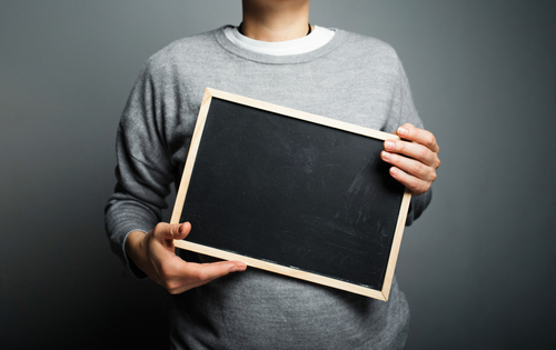 Picture of a male - head not visible - in grey sweater holding a blank slate.